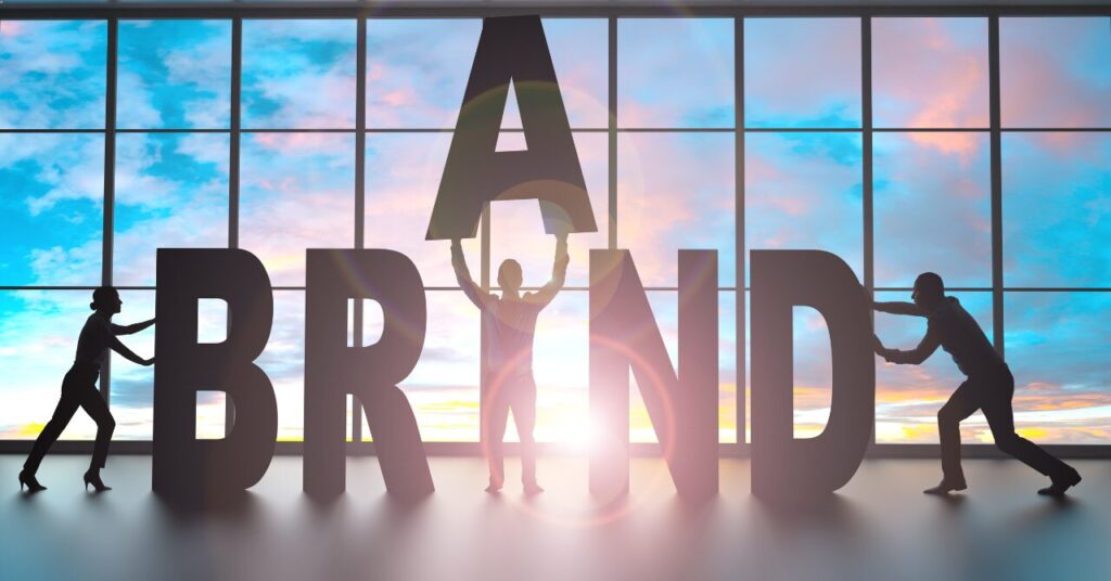 「BRAND」の文字を人々が協力して組み立てているシルエット画像。ブランド構築やチームワークを象徴したビジュアル。