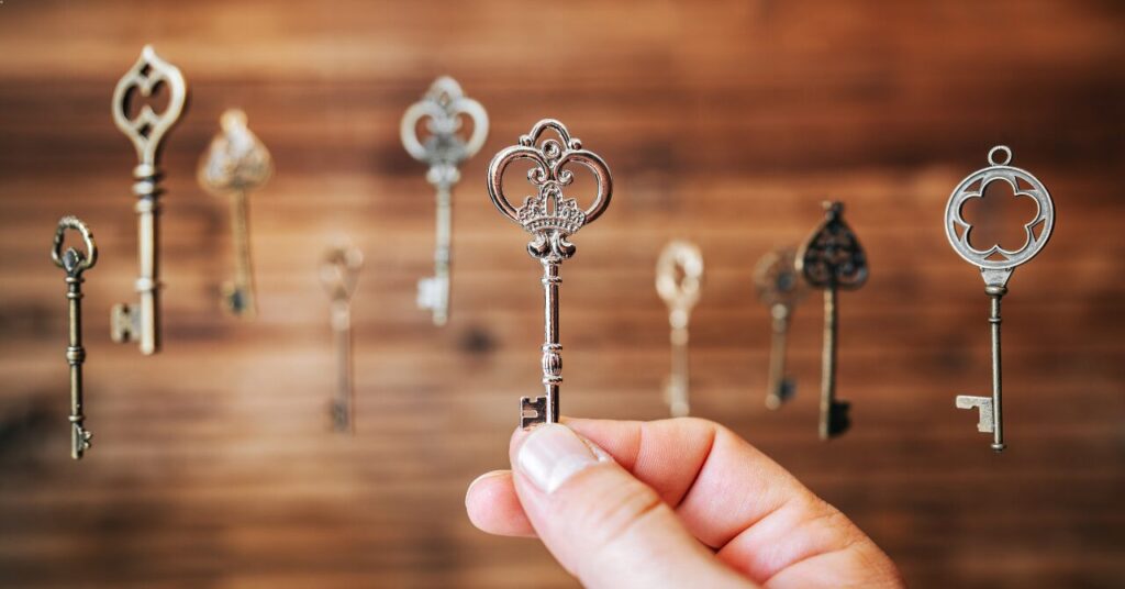 複数の鍵の中から1本を選んで持つ手の写真。自分に合った正解を見つける、選択や判断を象徴するイメージ。