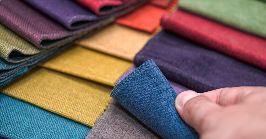色や質感の違う布サンプルを手に取っている写真。リカバリーウェアのブランド別・素材別のポイントを説明するためのイメージ画像