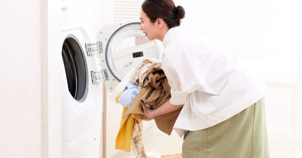 洗濯機に衣類を入れる女性の写真|ベネクスを長持ちさせるためのお手入れイメージ