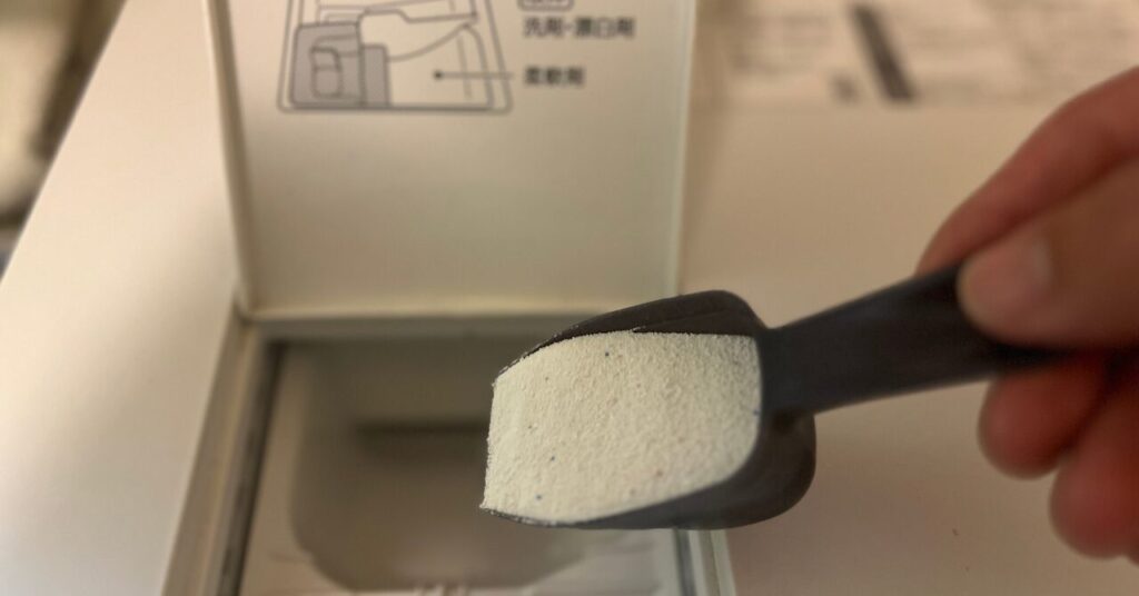 粉末洗剤を洗濯機に入れる手元の写真|強い洗剤をうっかり使ってしまった場合のイメージ
