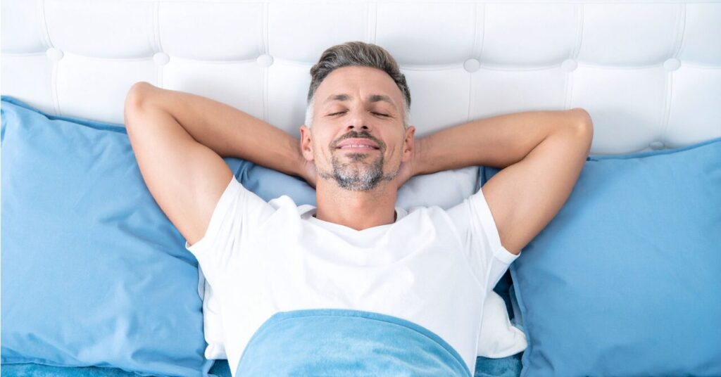 ゆったりサイズのリカバリーウェアでリラックスして寝ている40代男性のイメージ写真