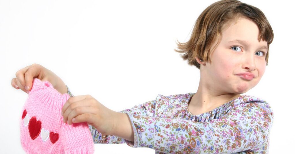 セーターが縮んだか心配そうに確認する子どもの写真。洗濯による縮みのイメージ。