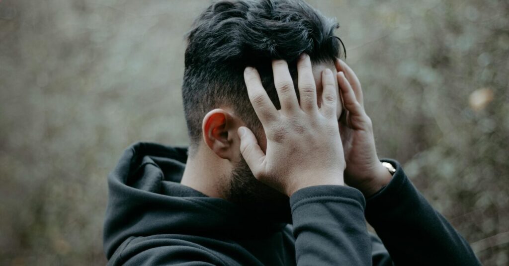 頭を抱えて反省する男性。リカバリーウェア選びでのありがちな失敗をイメージした写真。