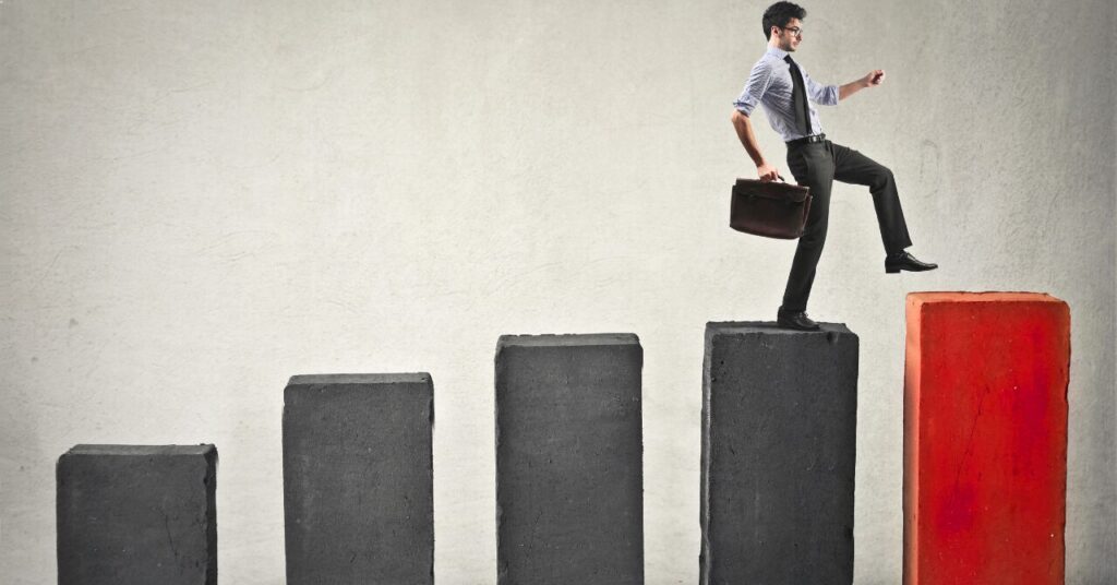 一歩ずつ階段を上がるビジネスマンの姿。リカバリーウェアのサイズ選びを5つのステップで順に進めるイメージ。