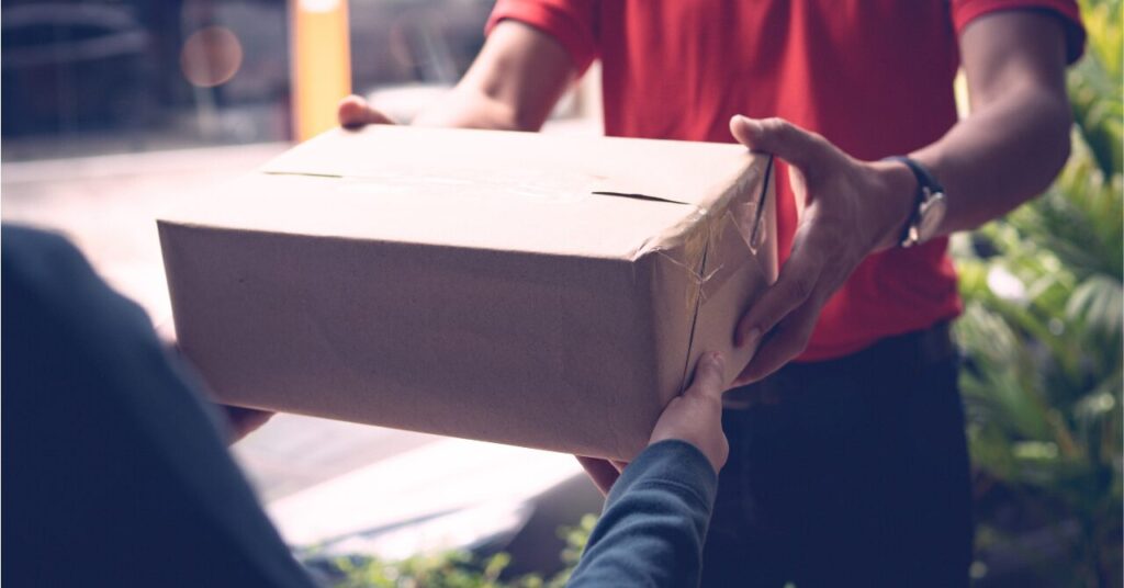 配送員から荷物を受け取る手元の写真。サイズが合わなかったときの返品・交換を意識したイメージ。